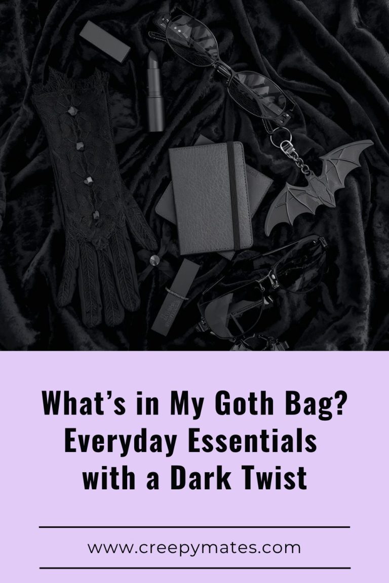 Goth flat lay with black lace glove, sunglasses, notebook, lipstick, and a bat keychain on black velvet.